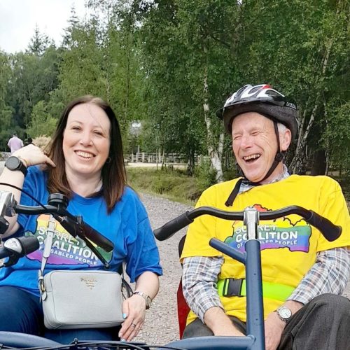 Two people smiling on a two person bike in Alice Holt Forest.