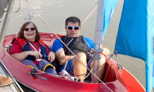 Staff member Angie in a sailing boat with a volunteer