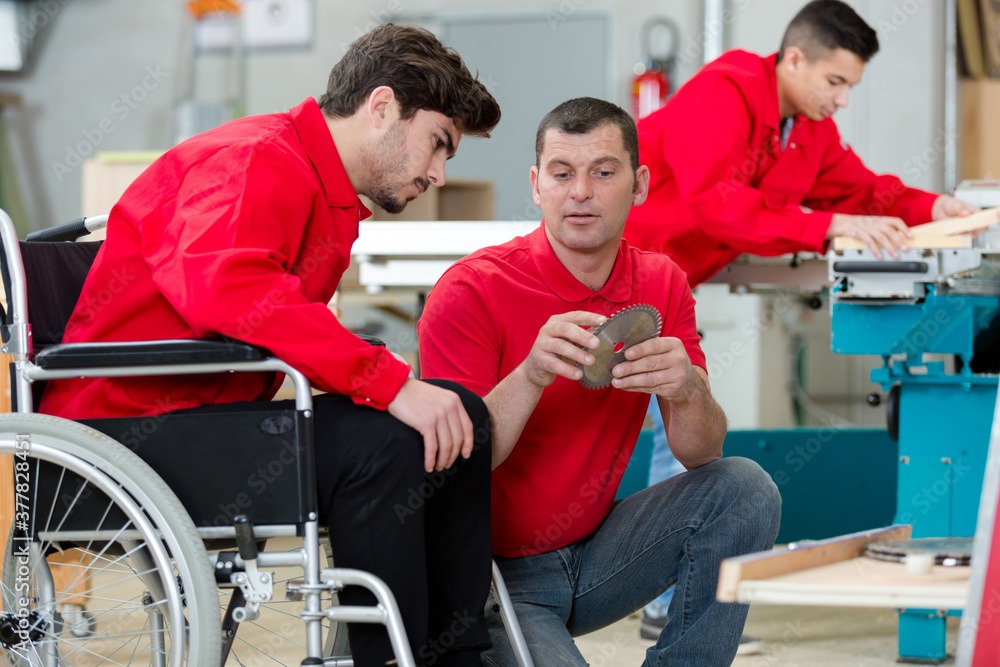 Wheelchair user with colleagues in a workshop environment 