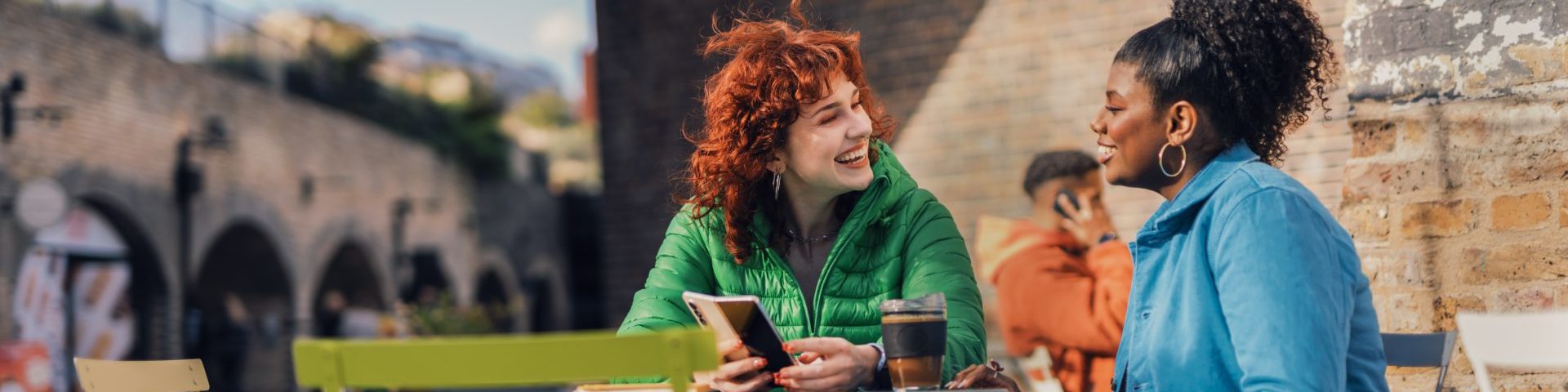 Two women talking and sat outside at a cafe