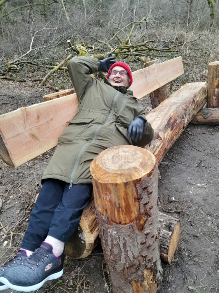 Coalition member Anna smiling on a new bench at Newlands Corner. 