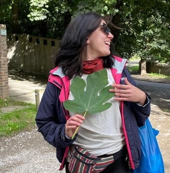 Photo of Charlotte smiling and holding a very large leaf 