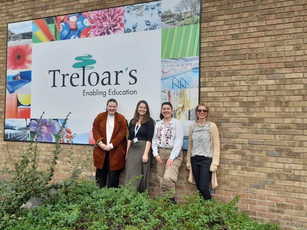 Coalition staff members Alex, Jasmine, Charlotte and Nikki in front of a large Treloar's sign