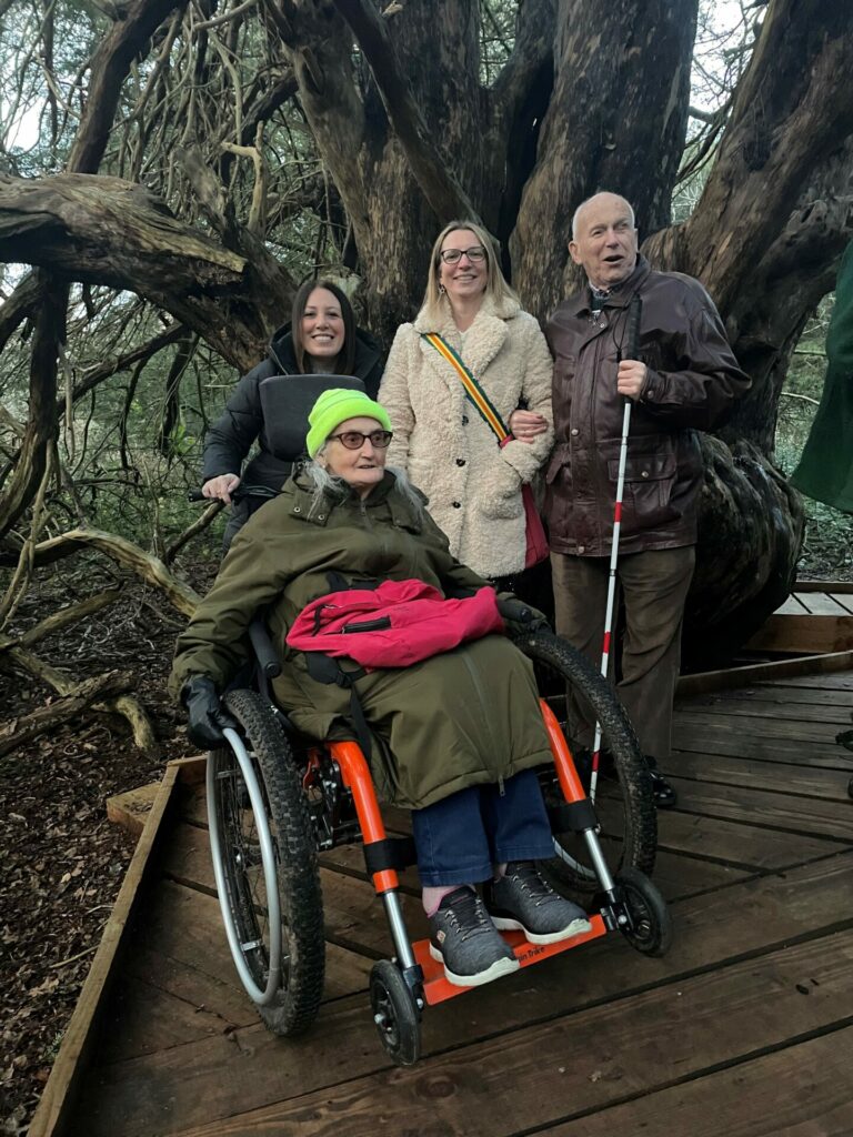 Coalition staff Nikki and Yasmin with two Coalition members on a boardwalk in front of a huge tree. 