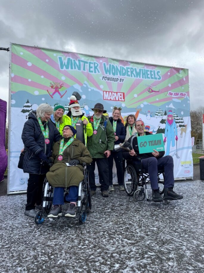 Coalition staff and members in front of a winter wonderwheels banner with fake snow falling. 