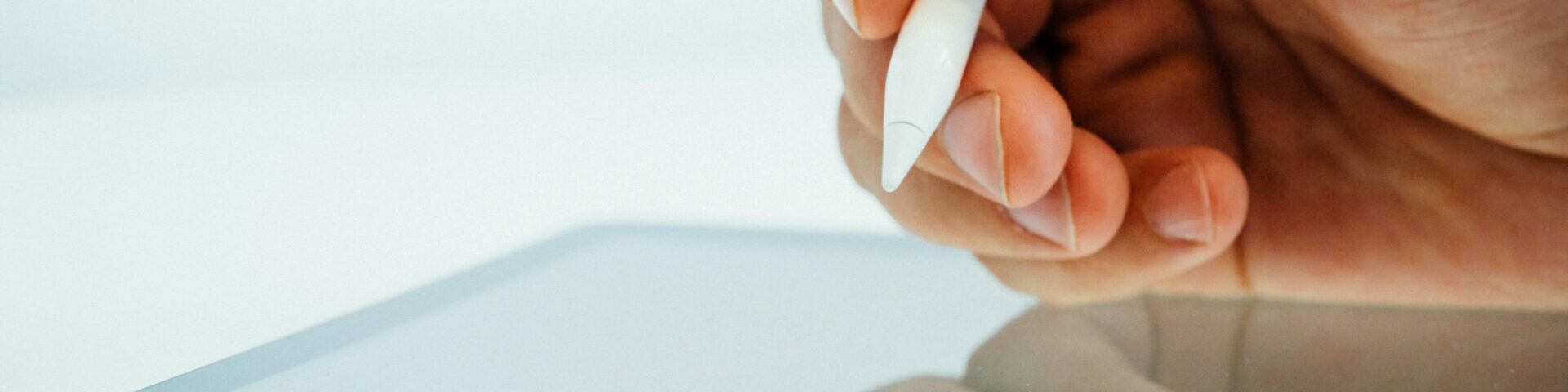 close up image of a hand using a stylus pen on a digital tablet.