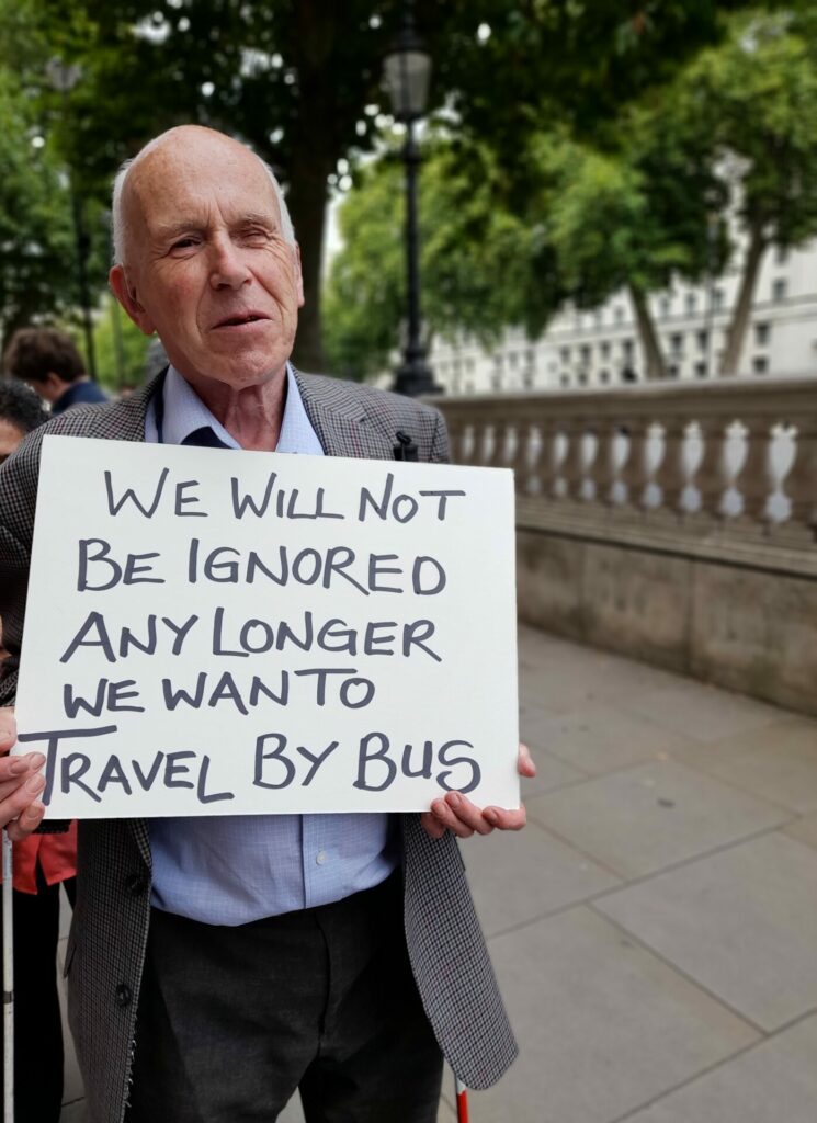 Coalition member, Jonathan at a campaigns trip in London, telling the government about the safety problems of floating bus stops. Jonathan is holding a sign with the words 'We will not be ignored any longer we want to travel by bus'.