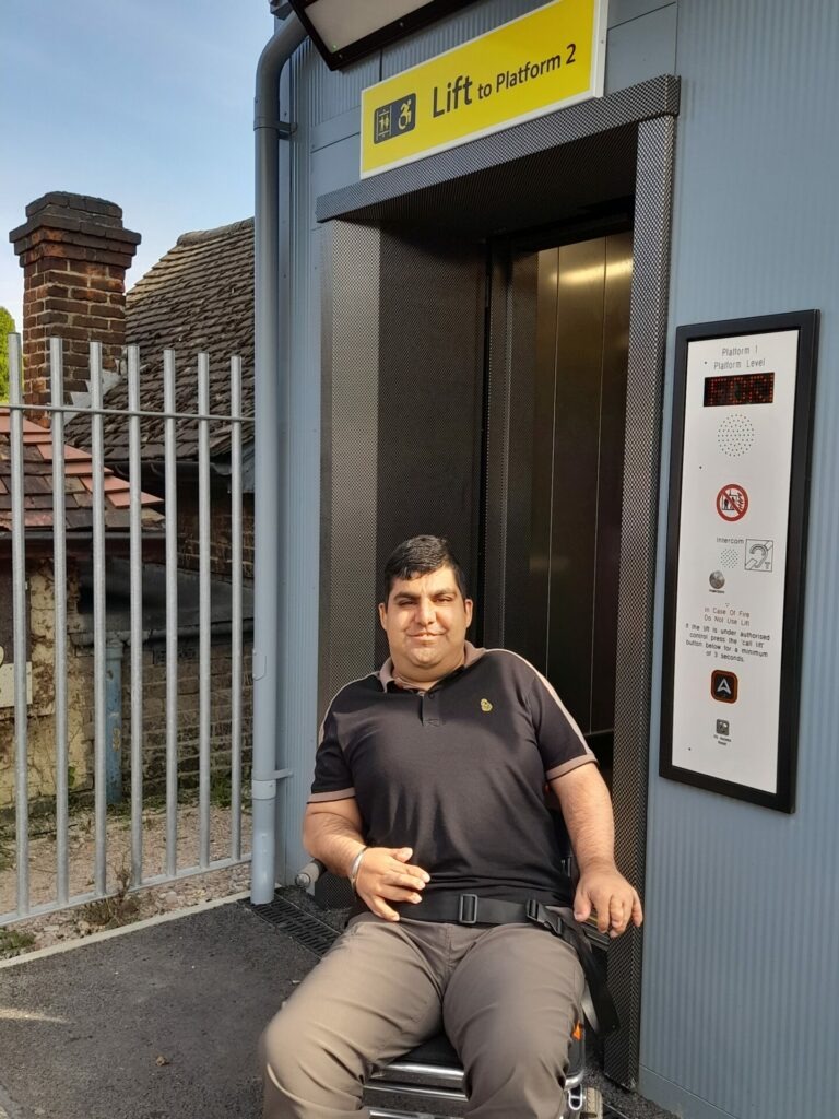 Coalition member, Carinder, who is a wheelchair user in front of the new lift at Walton-on-Thames station. 